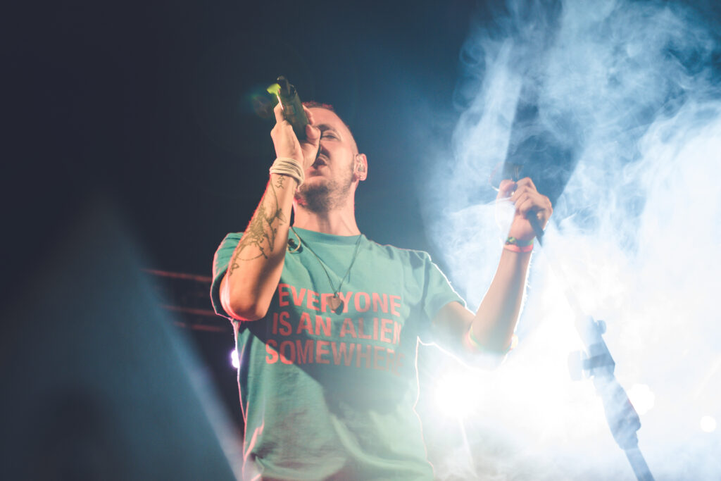 cantante del tributo ai Coldplay durante un concerto fra giochi di luce e macchine del fumo