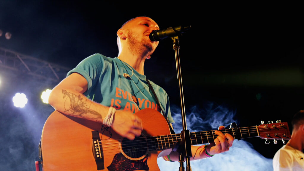 il cantante Alex suona la chitarra acustica e canta durante un live tributo ai Coldplay