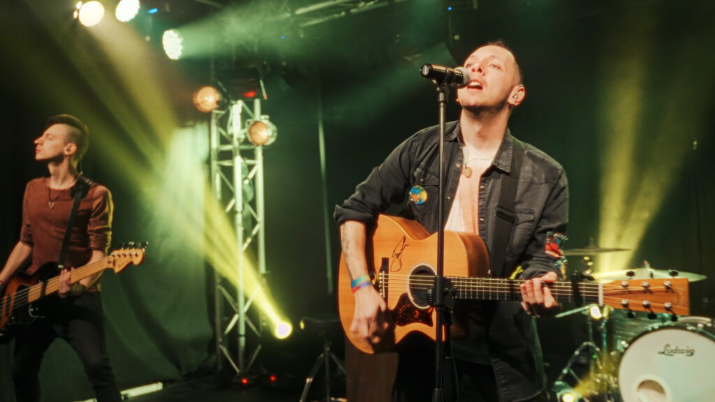 il cantante dei paradise canta e suona la chitarra acustica durante un concerto live